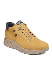 Zapatilla alta de gamuza marrón claro con una suela texturizada beige, que presenta ojales metálicos, cordones redondos y un collar acolchado negro. Logo en la lengüeta.