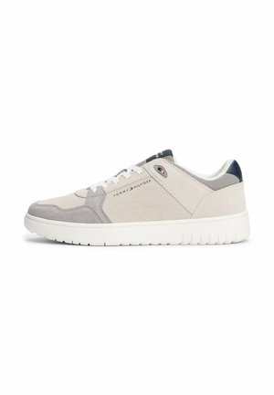 Sneaker gris clair en maille et daim avec une semelle en caoutchouc blanche. Présente un accent bleu marine au talon et un détail de logo sur le côté.