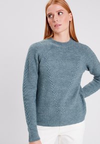 Lichtblauw gebreid sweater met een textuurpatroon, ronde halslijn en geribde manchetten. Kabelbrei-accents langs de zijkanten.