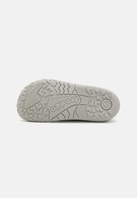 Semelle en caoutchouc gris avec des motifs texturés pour l'adhérence, portant un logo imprimé sur le demi-guide et un design à bout rond.