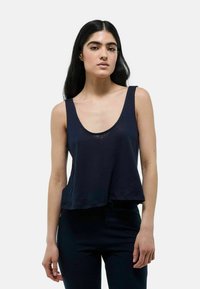 Débardeur bleu marine sans manches avec un col en rond, coupe décontractée et tissu doux et texturé. L'ourlet tombe juste au-dessus de la taille.