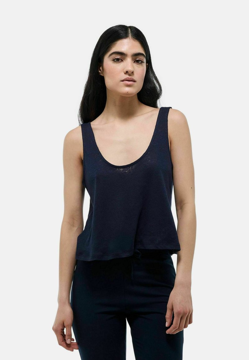 Débardeur bleu marine sans manches avec un col en rond, coupe décontractée et tissu doux et texturé. L'ourlet tombe juste au-dessus de la taille.