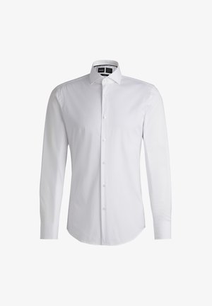 Chemise blanche à manches longues avec un col pointu, faite en tissu lisse. Présente un ourlet incurvé et des boutons nacrés sur le devant.