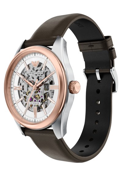 Automatické náramkové hodinky Emporio Armani s průhledným ciferníkem, růžově zlatým rámečkem, stříbrným pouzdrem a tmavě hnědým koženým řemínkem.