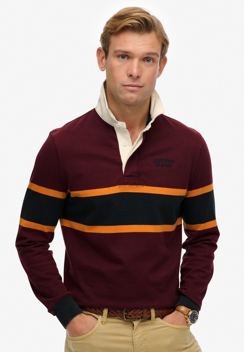 Bordeaux langærmet polo skjorte med en creme farvet krave, prydet med sorte og orange vandrette striber samt broderet logo detaljer på brystet.