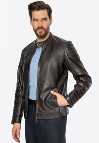 Giacca da moto in pelle marrone con dettagli a coste sulle spalle, colletto alto e tasche con zip. Texture liscia con un design aderente.