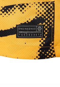 Tissu jaune avec une surface texturée, présentant un motif de tache noire et une étiquette noire sur laquelle est inscrit "ENGINEERED TS529336TB."