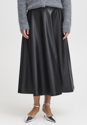 Zwarte leren rok met een vloeiende ontwerp, gladde textuur en een knielange snit. Gecombineerd met zilveren puntenhakken. Grijs gebreid topje is zichtbaar.