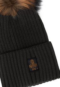 Berretto a coste nero con pompon in finta pelliccia marrone e una piccola etichetta raffigurante un cane che tiene in mano un cartello "RegigliWear".