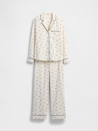 Ensemble de pyjama en tissu crème avec un petit motif floral, composé d'une chemise à col et d'un pantalon à cordon de serrage avec une bordure verte contrastante.