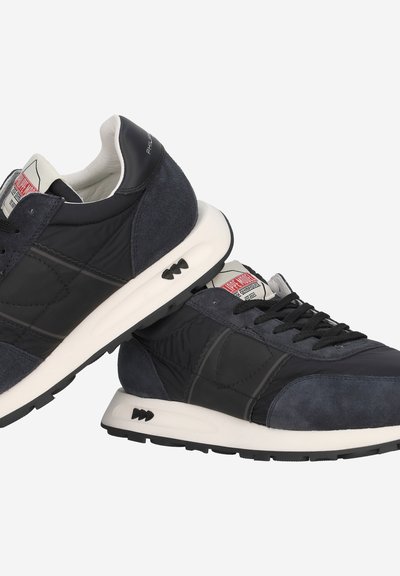 Sneaker di un blu scuro, realizzate con un mix di suede e materiali sintetici, con accenti testurizzati, lacci neri e una suola bianca a contrasto.
