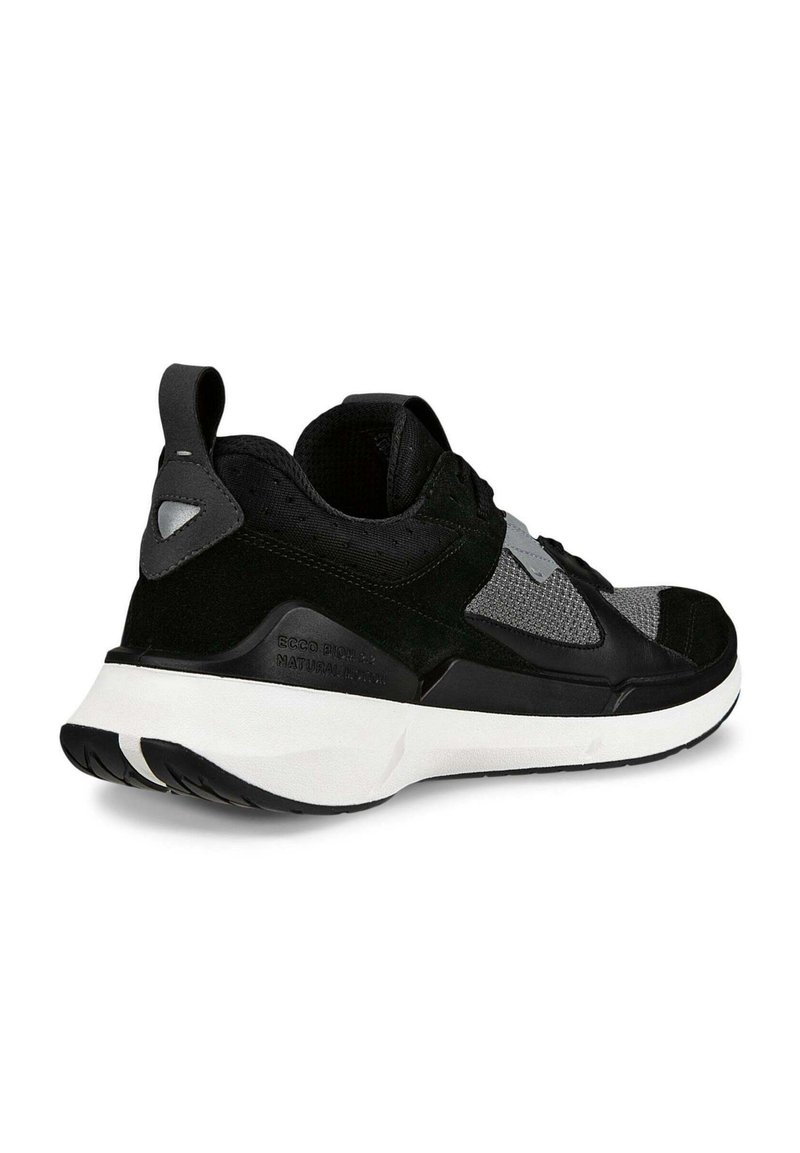 Schwarzer und grauer Sneaker aus Mesh- und Wildledermaterialien, mit einer robusten weißen Sohle und einer Ziehschlaufe an der Ferse für einfaches Anziehen.