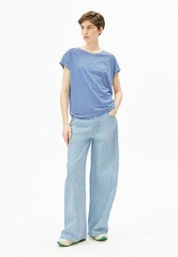 Blauw-wit gestreept kortärmlig shirt gecombineerd met hoge taille, wijde lichtblauwe jeans. De outfit heeft een ontspannen pasvorm en minimale details.