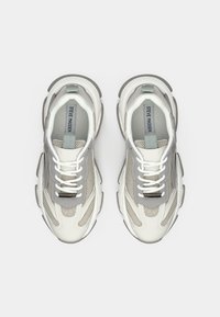 Par bijelih i sivih Steve Madden chunky tenisica s mrežastim i kožnim detaljima, snimljenih odozgo na bijeloj pozadini.