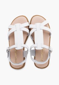 White leather sandals featuring cross straps, a cushioned insole, and a brown rubber outsole with an adjustable ankle buckle.