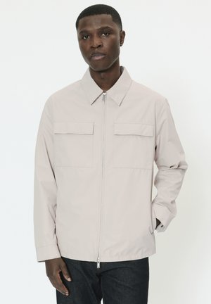 Svetlobéžová bunda s golierovým výstrihom, dlhými rukávmi, dvoma náprsnými vreckami a predným zipsom. Hladká textúra, ležérny dizajn.