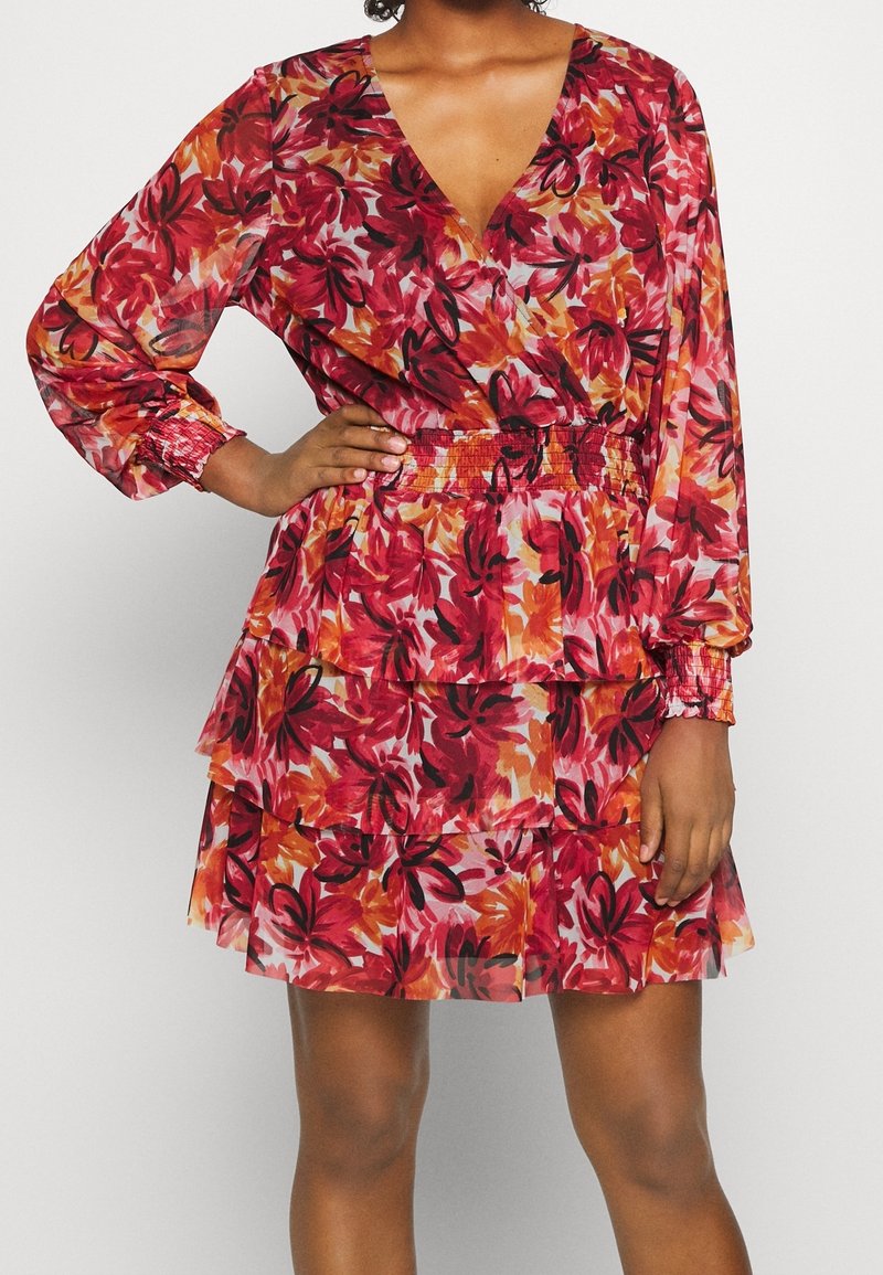 Vestido floral con escote en V profundo, mangas largas y cintura fruncida. Presenta volantes en capas con patrones vibrantes en rojo, naranja y rosa.