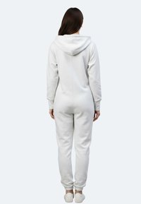 Tutina in pile grigio chiaro con cappuccio, gambe affusolate, polsini elastici e una superficie liscia, caratterizzata da un design con cucitura sul retro.