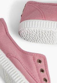 Baskets slip-on en toile rose avec semelles en caoutchouc blanches, dotées de coutures ton sur ton et d'œillets en bronze. Semelle texturée pour une meilleure adhérence.