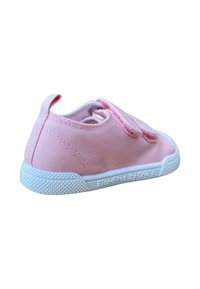 Zapatilla de lona rosa con superficie texturizada, cordones elásticos, suela de goma blanca y tira en el talón. La marca es visible en el costado.