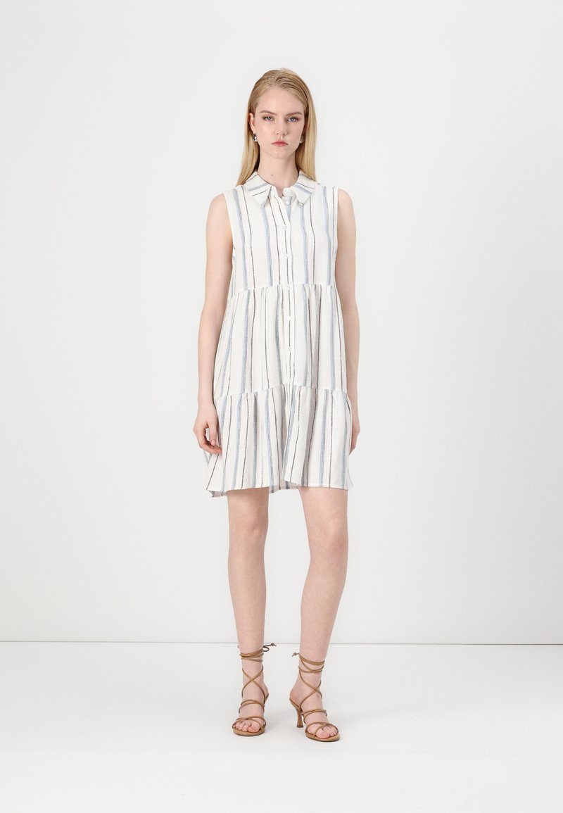 Robe sans manches blanche avec des rayures verticales bleues, devant boutonné, jupe froncée et coupe décontractée. Portez-la avec des sandales bronzées à lanières.