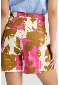 Pantaloni corti floreali con una stampa botanica audace in rosa e marrone su sfondo crema, realizzati in un tessuto leggero con tasche e vita aderente.