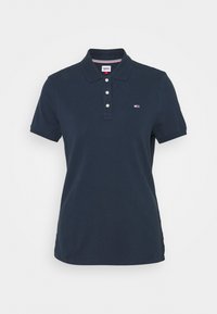 Mörkblå polo-shirt i bomull med ribbad krage, tre-knapps knäppning och en liten logotyp på vänster bröst. Korta ärmar.