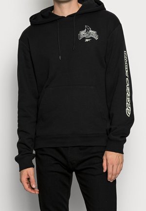 Person trägt einen schwarzen Hoodie mit Power Rangers-Logo auf der Brust und dem Schriftzug "Dirty Thirty" auf dem rechten Ärmel.