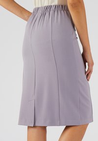 Gonna lavanda a lunghezza ginocchio con elastico in vita, caratterizzata da pieghe laterali e una texture liscia e leggera. Design semplice e funzionale.