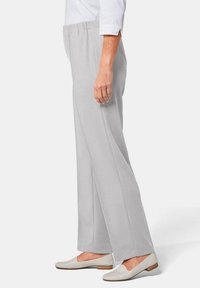 Lichtgrijze, lichte ribbroek met een elastische tailleband, voorzien van een rechte pijp en een zachte textuur. Gecombineerd met platte, lichte schoenen.