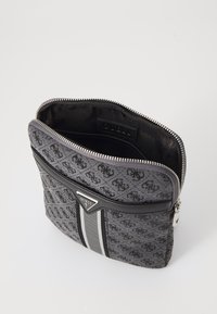 Estuche con cremallera en negro y gris que presenta un patrón de logotipos, herrajes plateados y un acento de rayas horizontales en la parte frontal.