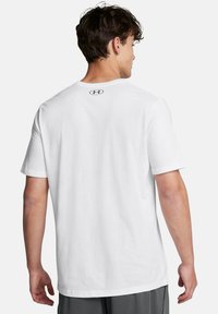Camiseta de algodón blanca de manga corta con cuello redondo y un pequeño logo en la parte trasera, diseño liso y corte relajado.