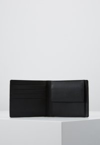 Black leather wallet featuring multiple card slots, a fold-over flap, and a smooth texture. Compact design with subtle stitching details.