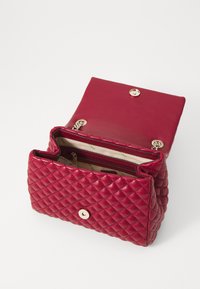 Borsa a tracolla in pelle rossa trapuntata con chiusura a scatto dorata, dotata di un ampio interno con una tasca con zip e foderata con un tessuto chiaro.