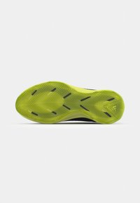 Sole di scarpa da atletica nera con una suola in gomma giallo-verde brillante. Presenta un motivo a zigzag e sezioni scure per una migliore aderenza.