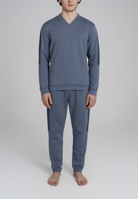 Felpa azzurra chiara e pantaloni abbinati in morbido tessuto. Design a V, maniche lunghe e pannelli laterali sui pantaloni. Estetica minimalista.