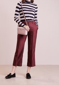 Maglione a collo alto a righe blu e bianche, pantaloni bordeaux su misura, mocassini neri e una piccola borsa a tracolla rosa chiaro.