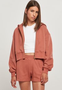 Laksrosa cropped hettegenser med glidelås, ballongsleeves og matchende shorts. Mykt stoff og avslappet passform med elastisk midje.