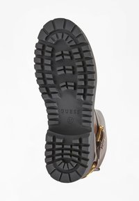 Suola di scarpa in gomma nera con battistrada profondo, marchio impresso "GUESS" e taglia "37." Presenta un bordo esterno liscio e un tallone rinforzato.