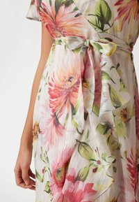 Vestido envolvente femenino con flores grandes en tonos rosa y naranja, hojas verdes y detalle de cinturón atado en la cintura.