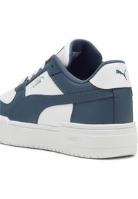 Baskets Puma avec un dessus en cuir bleu marine et blanc, présentant un design texturé, un col rembourré et le logo emblématique sur le talon.