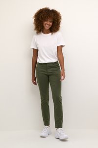 Olive green slim-fit pants with smooth texture, featuring a waistband and front pockets, paired with a plain white t-shirt and white sneakers.