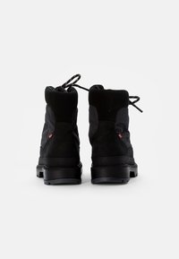 Botas negras con un empeine texturizado, cuello acolchado y suelas de goma resistentes. Presentan costuras reforzadas y cordones negros en la parte trasera.