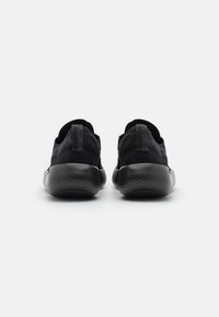 Schwarze Sportschuhe mit einem strukturierten Strick-Obermaterial und einem Zugtab. Sie verfügen über eine dicke, gepolsterte Sohle mit einem strukturierten Grip.