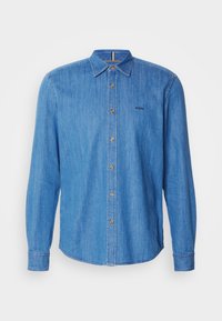 Camicia in denim blu chiaro con maniche lunghe, chiusura a bottoni e colletto a punta. Presenta bottoni dorati e un logo del marchio sottile.