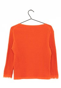 Pull en tricot côtelé orange à manches longues, col large et détails à franges aux bords des poignets. Suspendu à un crochet noir.