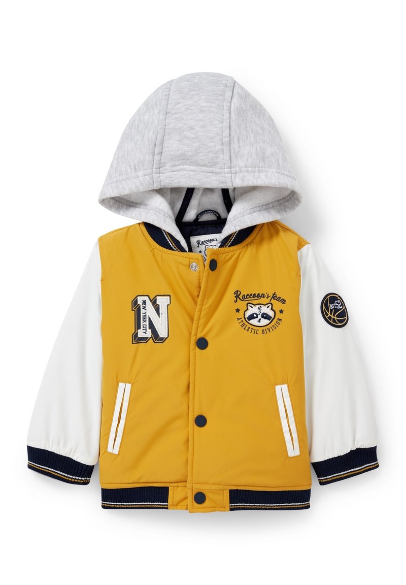 Żółta i biała kurtka z szarym kapturem, wyposażona w naszywkę z logo, haftowane wzory, guziki zatrzaskowe oraz ściągacze przy mankietach.