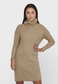 Strikket beige høyhalset kjole med lange ermer, ribbestruktur og løs passform, som når midt på låret. Minimalistisk design uten merkbare detaljer.
