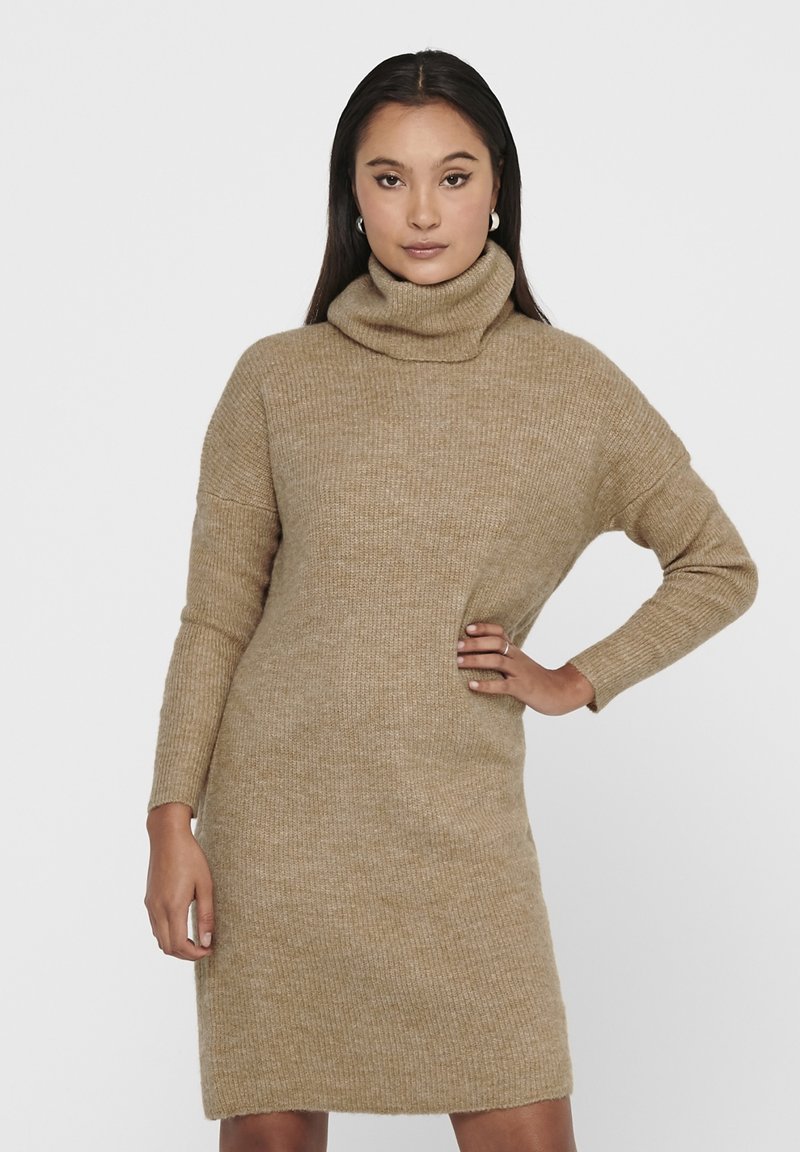 Strikket beige høyhalset kjole med lange ermer, ribbestruktur og løs passform, som når midt på låret. Minimalistisk design uten merkbare detaljer.