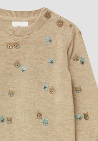Lichtbruine gebreide trui met kleurrijke borduursels van een berenkop en knoopaccenten op de schouder. Zachte textuur. Casual ontwerp.